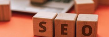 Wooden blocks spelling SEO on a laptop keyboard convey digital marketing concepts.